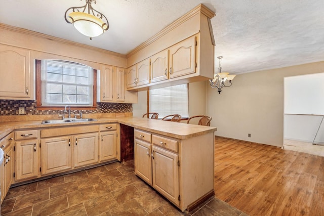 kitchen with backsplash, crown molding, sink, and pendant lighting