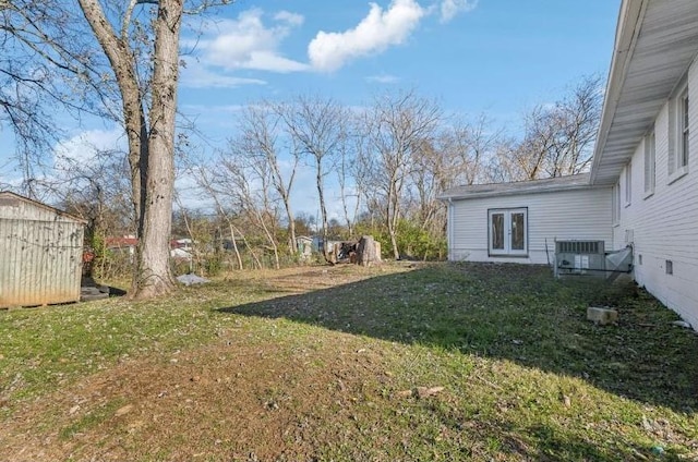 view of yard featuring central AC, french doors, and a shed