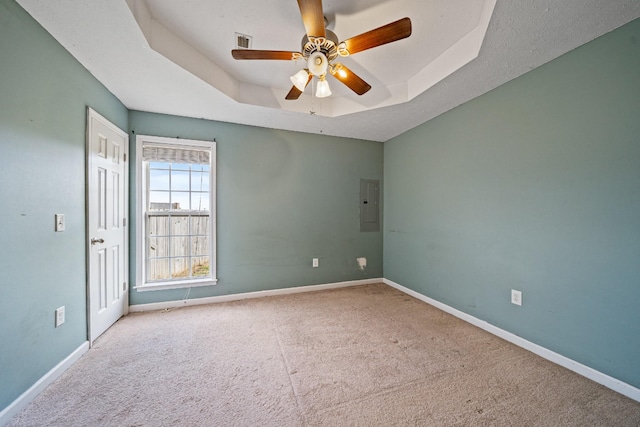 empty room featuring electric panel, light colored carpet, a raised ceiling, and ceiling fan