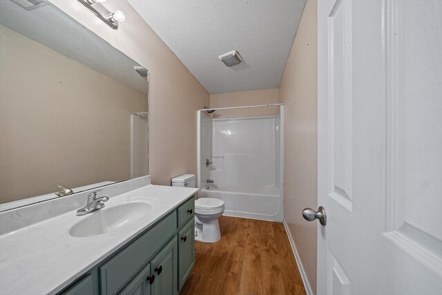 full bathroom featuring shower / bathing tub combination, vanity, hardwood / wood-style flooring, toilet, and a textured ceiling