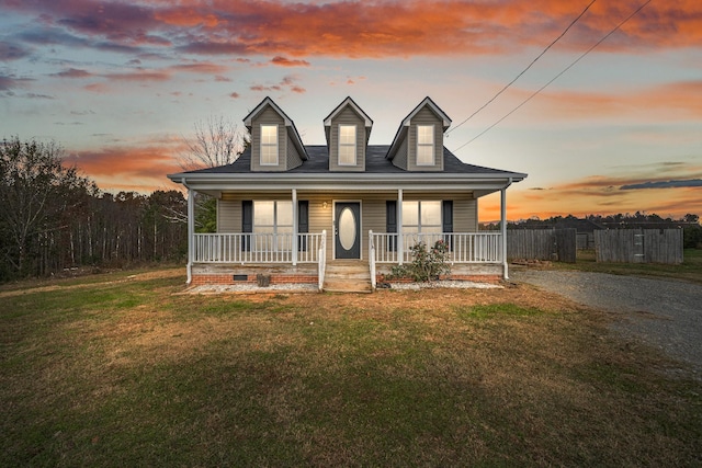 cape cod-style house featuring a porch and a yard