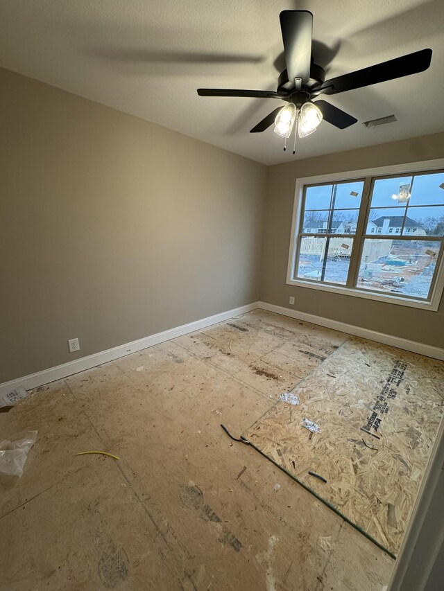 unfurnished room with visible vents, ceiling fan, a textured ceiling, and baseboards