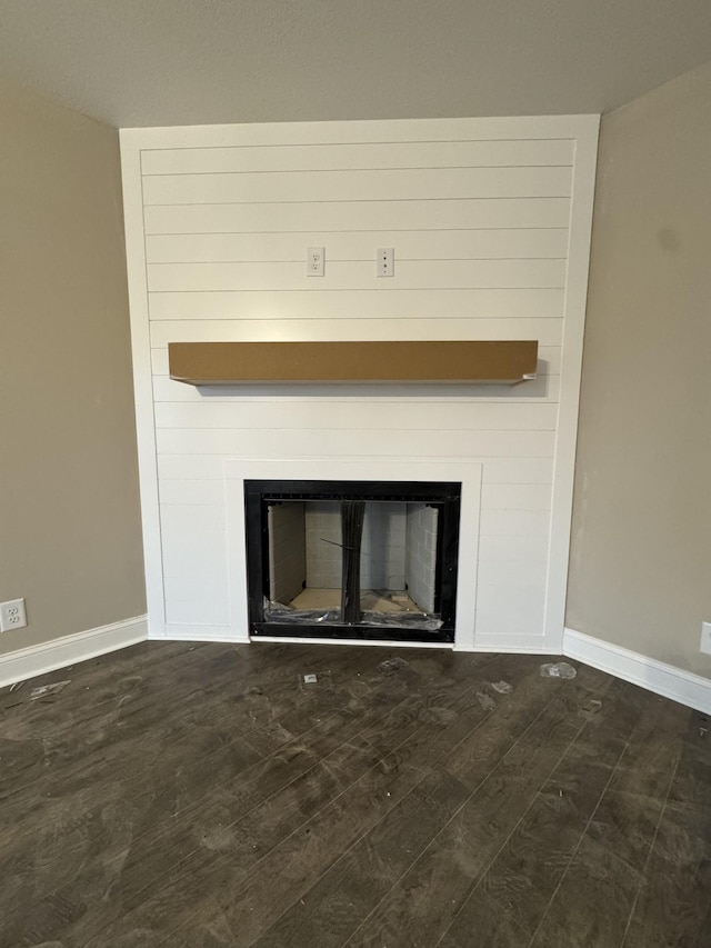 interior details with a glass covered fireplace, baseboards, and wood finished floors