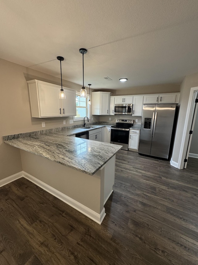 169 Anderson Pl, Clarksville, TN 37040 - kitchen featuring a sink, baseboards, dark wood finished floors, a peninsula, and appliances with stainless steel finishes