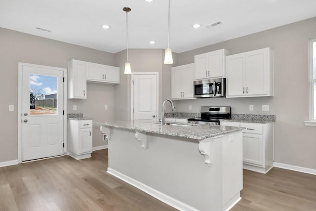 kitchen featuring white cabinets, a center island with sink, sink, and appliances with stainless steel finishes