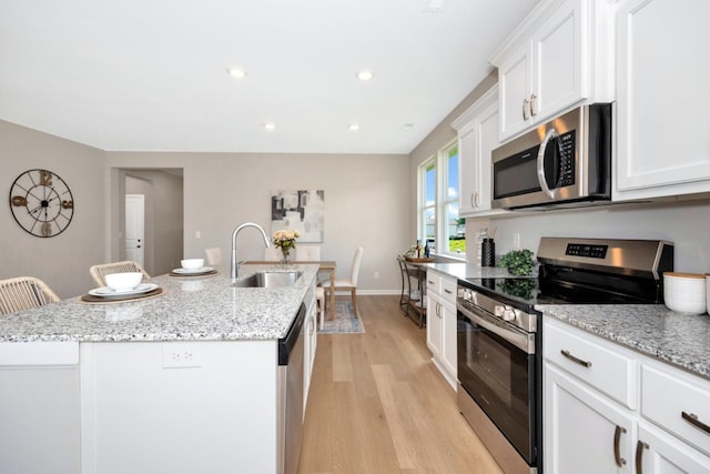 kitchen with sink, a kitchen breakfast bar, light hardwood / wood-style flooring, a center island with sink, and appliances with stainless steel finishes