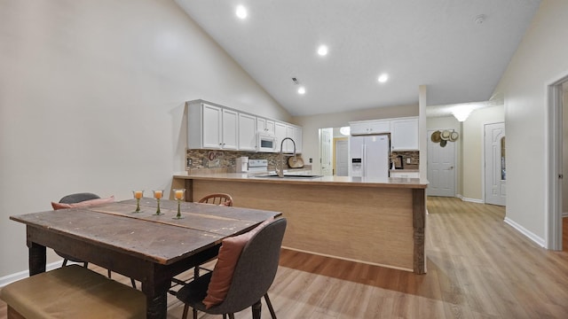 dining room with sink, high vaulted ceiling, and light hardwood / wood-style floors