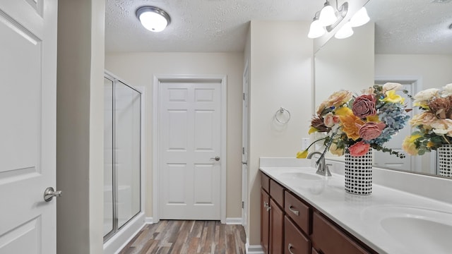 bathroom with vanity, wood-type flooring, a textured ceiling, and walk in shower