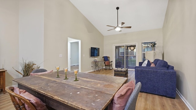 dining area with light wood-type flooring, high vaulted ceiling, and ceiling fan