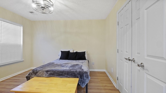 bedroom with a textured ceiling, hardwood / wood-style flooring, and a closet