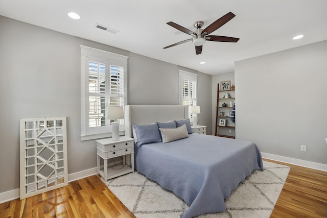 bedroom with multiple windows, wood-type flooring, and ceiling fan