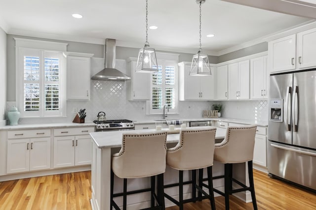 kitchen featuring white cabinetry, plenty of natural light, wall chimney exhaust hood, and stainless steel appliances