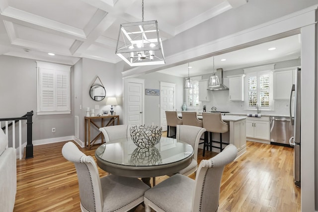 dining space with beam ceiling, light hardwood / wood-style flooring, coffered ceiling, and sink