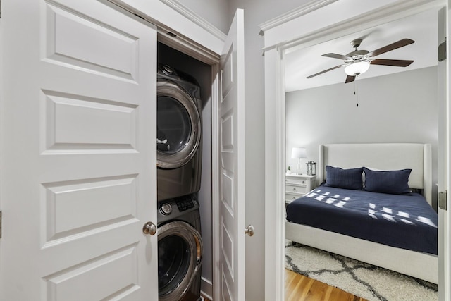 clothes washing area featuring stacked washing maching and dryer, light hardwood / wood-style flooring, and ceiling fan