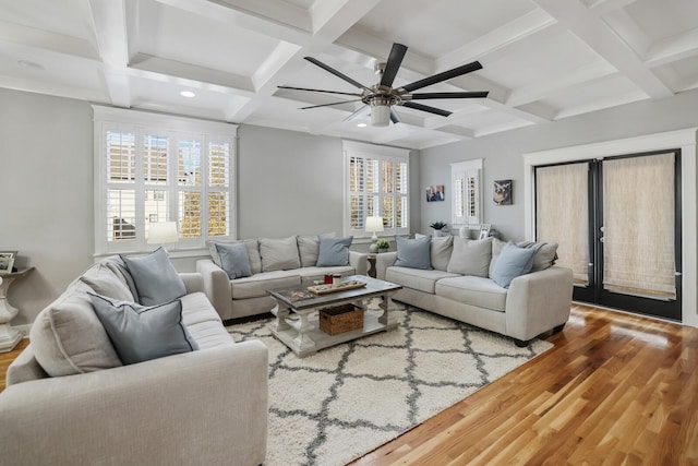 living room with a wealth of natural light, beamed ceiling, coffered ceiling, and hardwood / wood-style flooring