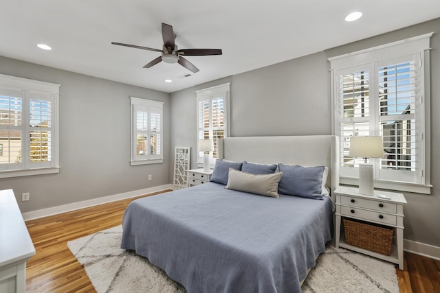 bedroom with hardwood / wood-style floors, ceiling fan, and multiple windows