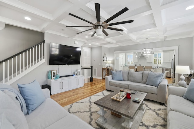 living room featuring ceiling fan, sink, coffered ceiling, beamed ceiling, and light hardwood / wood-style floors