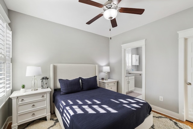 bedroom with multiple windows, ensuite bathroom, ceiling fan, and light hardwood / wood-style floors