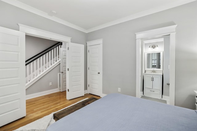 bedroom featuring wood-type flooring, ensuite bath, ornamental molding, and sink