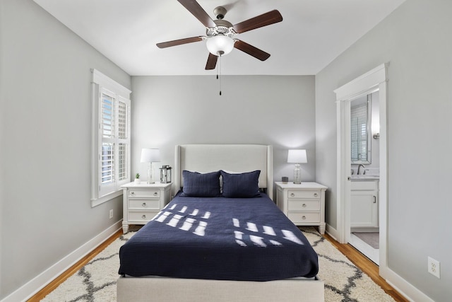 bedroom with ceiling fan, ensuite bath, sink, and light hardwood / wood-style flooring