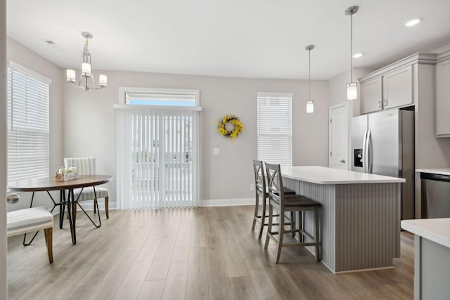 kitchen featuring light wood-type flooring, stainless steel appliances, hanging light fixtures, and gray cabinetry