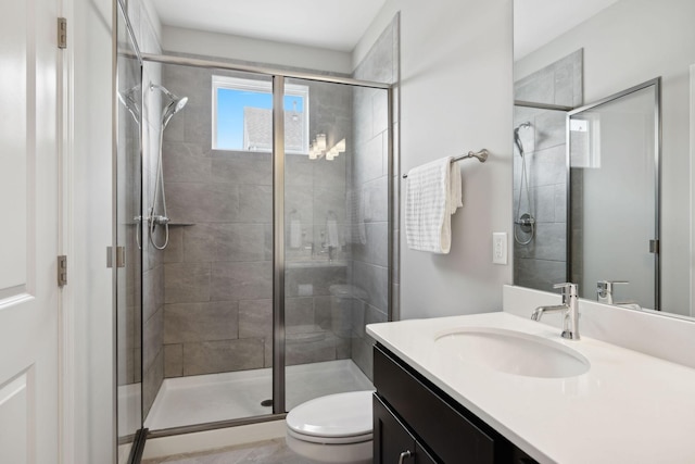 bathroom with vanity, a shower with shower door, and toilet