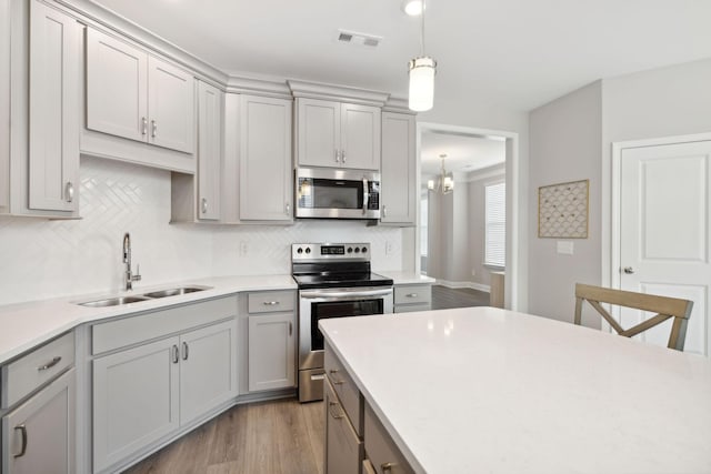 kitchen with hardwood / wood-style floors, stainless steel appliances, gray cabinetry, and sink