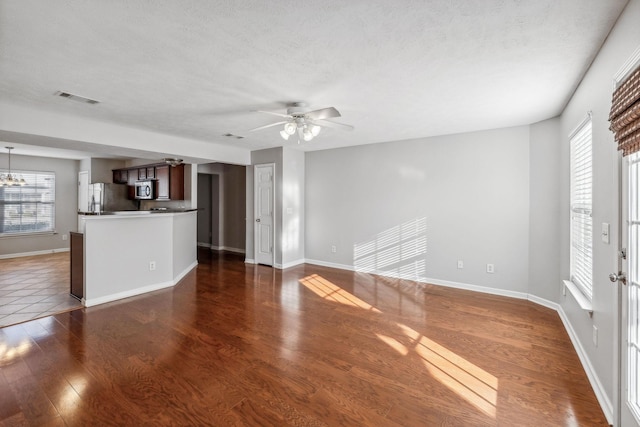 unfurnished living room featuring a textured ceiling, ceiling fan, and dark hardwood / wood-style floors