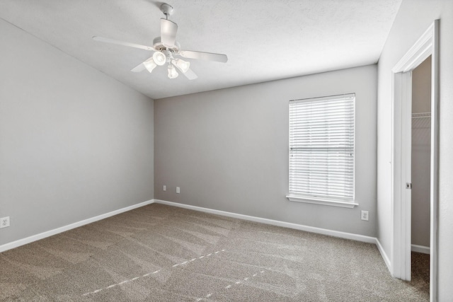 empty room with carpet flooring, ceiling fan, and a textured ceiling