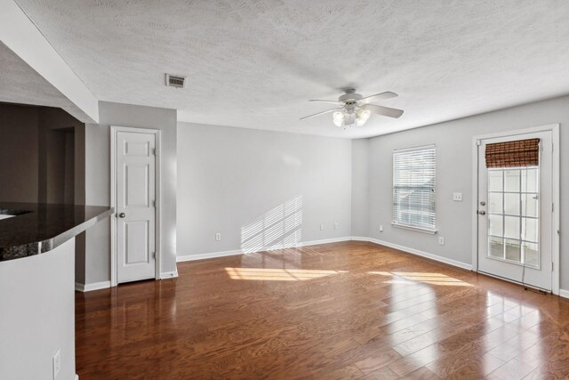 unfurnished living room featuring ceiling fan, dark wood-type flooring, and a textured ceiling