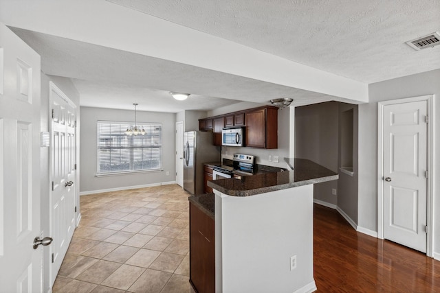 kitchen with hanging light fixtures, kitchen peninsula, light hardwood / wood-style floors, a textured ceiling, and appliances with stainless steel finishes