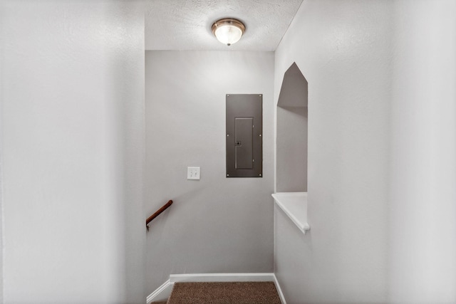 stairway with a textured ceiling and electric panel