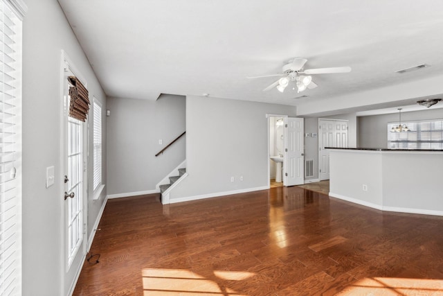 unfurnished living room featuring ceiling fan with notable chandelier, dark hardwood / wood-style flooring, and a healthy amount of sunlight