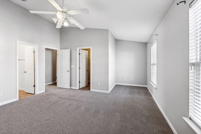 unfurnished bedroom with ceiling fan, vaulted ceiling, a walk in closet, a closet, and carpet