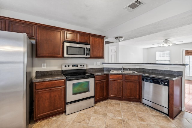 kitchen featuring kitchen peninsula, a textured ceiling, stainless steel appliances, ceiling fan, and sink