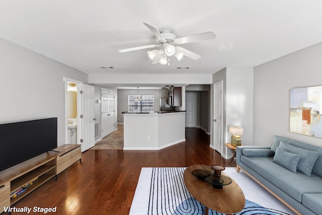 living room featuring visible vents, baseboards, wood finished floors, and ceiling fan with notable chandelier