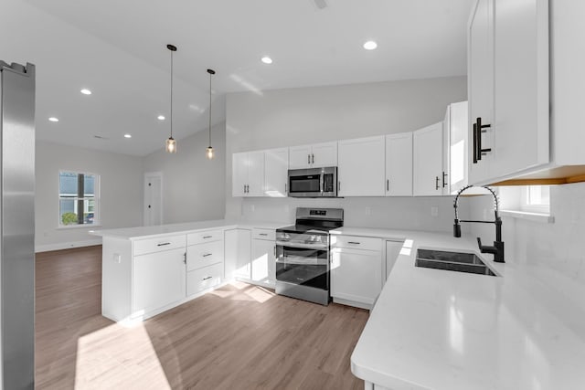 kitchen with sink, hanging light fixtures, kitchen peninsula, stainless steel appliances, and white cabinets