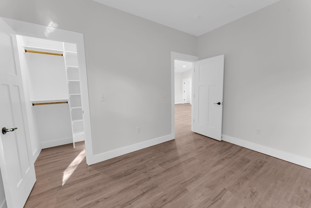 unfurnished bedroom featuring a walk in closet, light hardwood / wood-style floors, and a closet