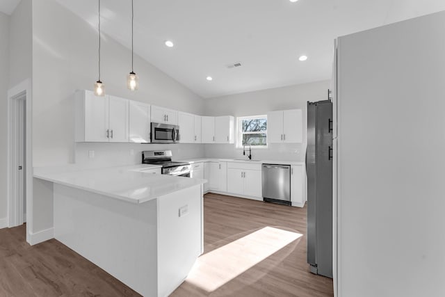 kitchen with stainless steel appliances, pendant lighting, white cabinets, and kitchen peninsula