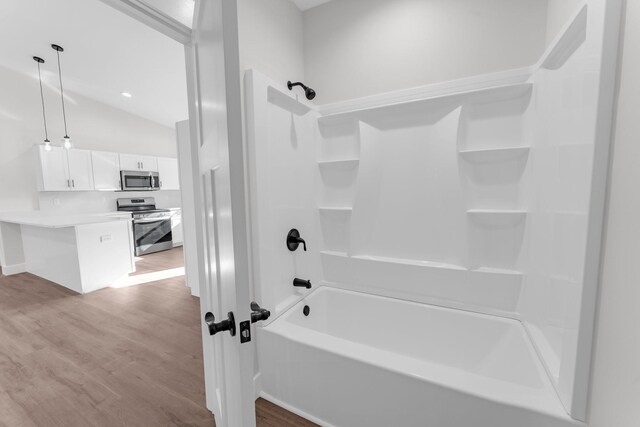 bathroom with hardwood / wood-style flooring, shower / bath combination, and vaulted ceiling