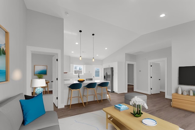 living room with sink, vaulted ceiling, and light hardwood / wood-style floors