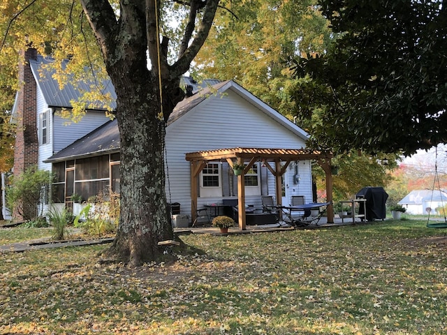 back of house with a pergola, a patio, a lawn, and a sunroom