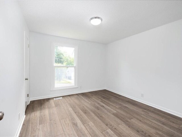 unfurnished room featuring wood-type flooring and a textured ceiling