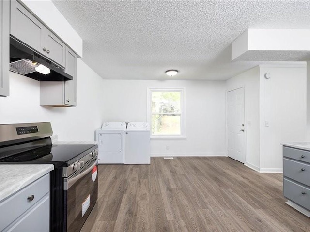 kitchen with separate washer and dryer, electric range, gray cabinets, and light wood-type flooring