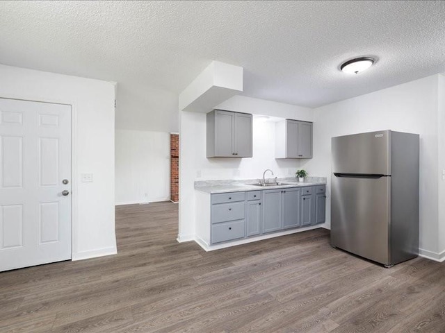 kitchen with dark hardwood / wood-style floors, sink, and stainless steel refrigerator