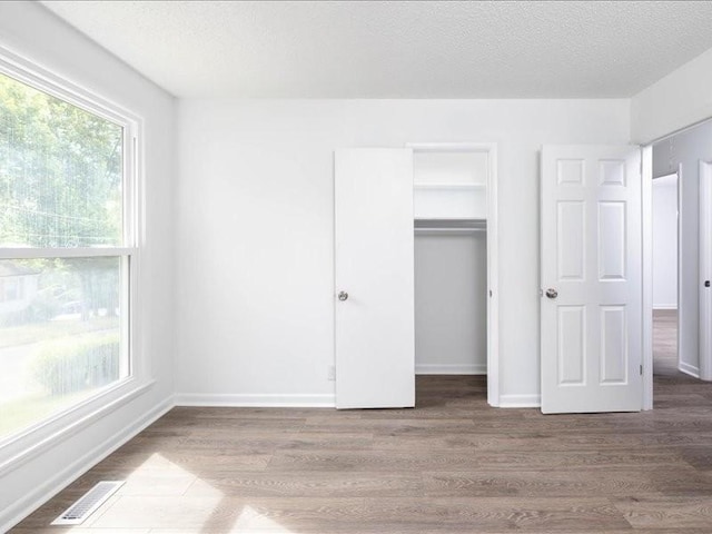 unfurnished bedroom with a closet, wood-type flooring, and a textured ceiling