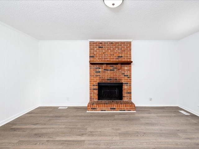 unfurnished living room with a fireplace, wood-type flooring, and a textured ceiling