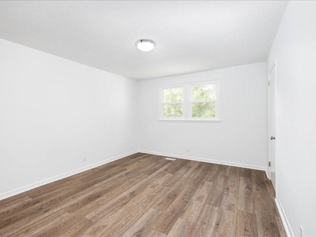 unfurnished room with hardwood / wood-style flooring and a textured ceiling