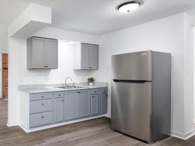 kitchen featuring gray cabinetry, dark wood-type flooring, sink, a textured ceiling, and stainless steel refrigerator