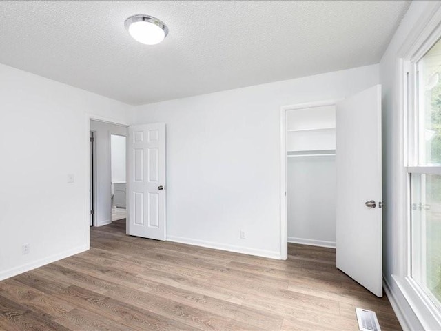 unfurnished bedroom with a textured ceiling, light hardwood / wood-style flooring, and a closet